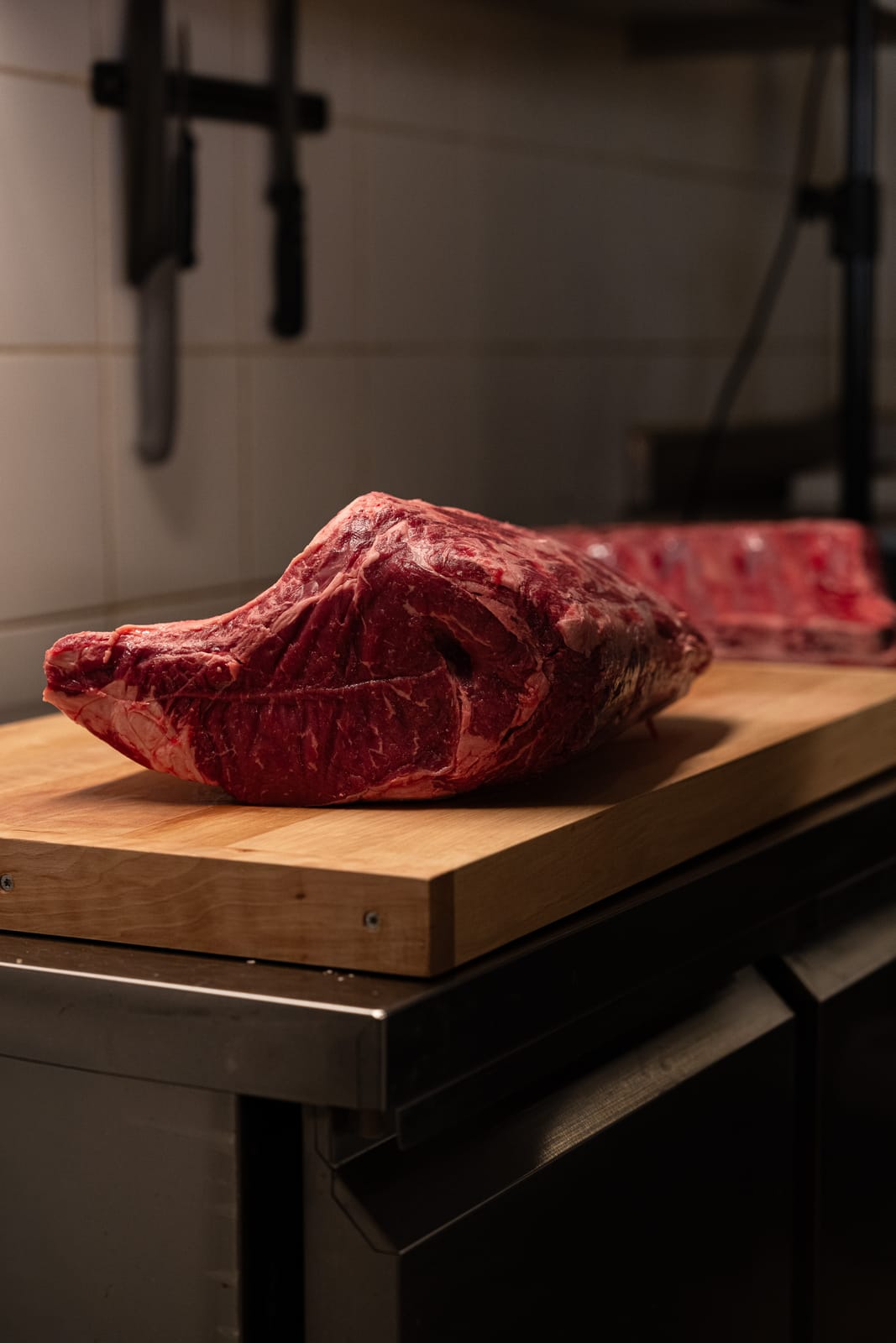 Pièce de côte de bœuf de race limousine crue, posée sur un billot en bois