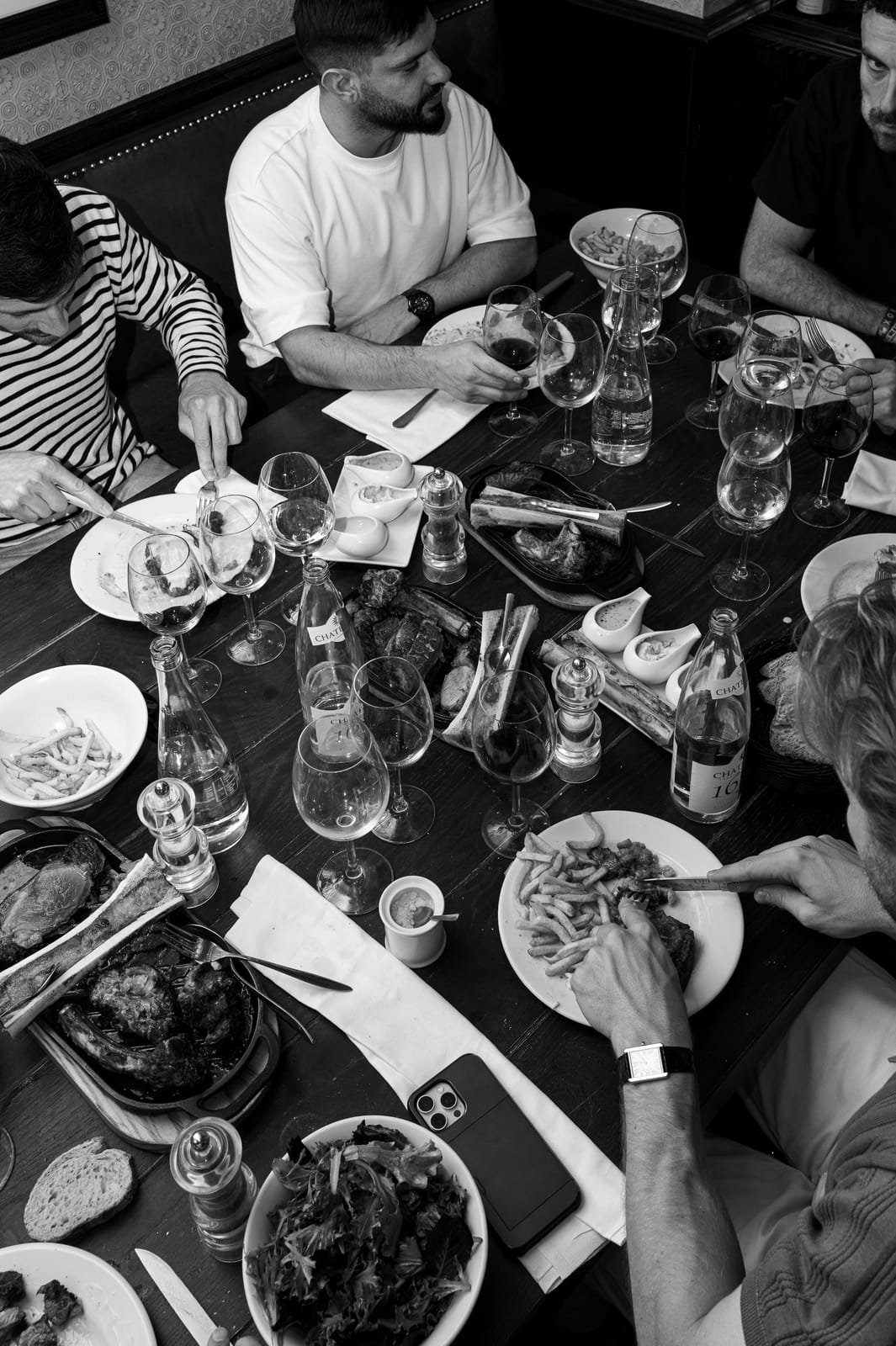 Tablée de convives partageant des côtes de bœuf, des frites et du vin chez À Côté