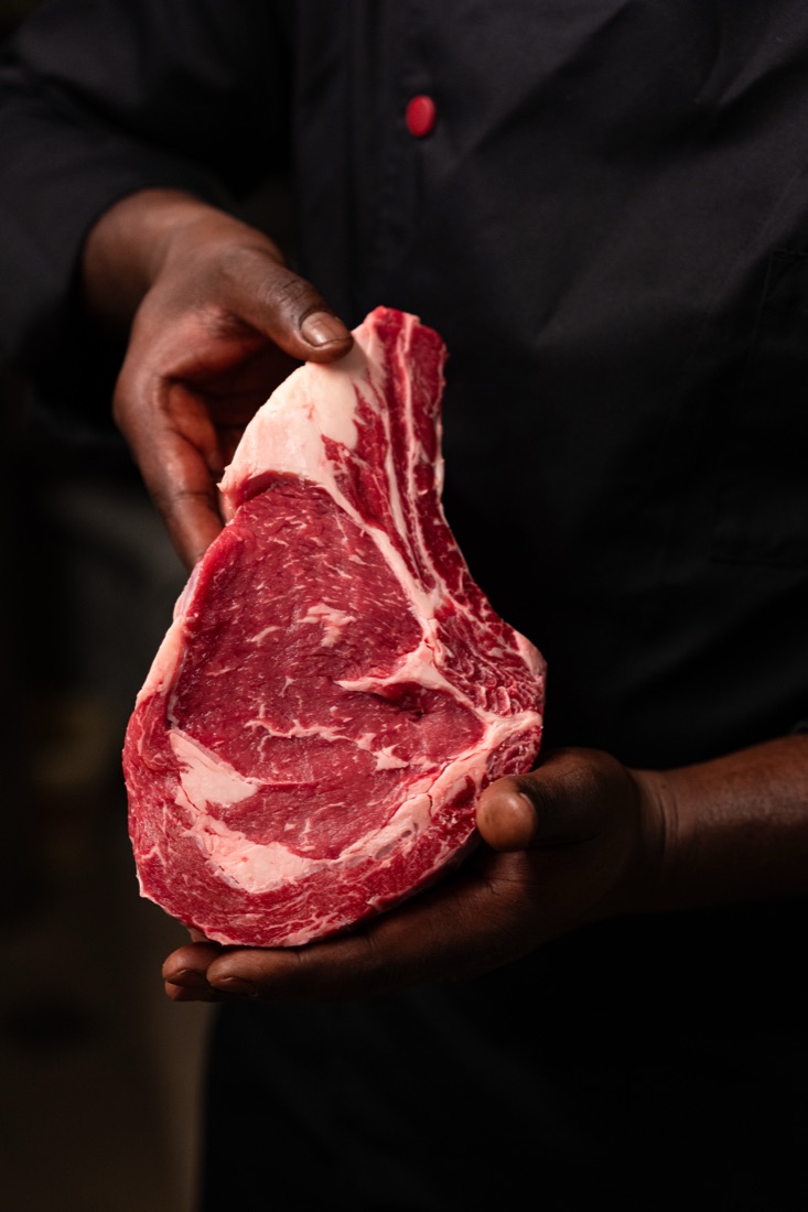 Côte de bœuf crue tenue à la main